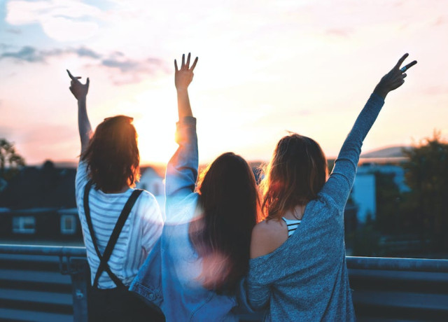 Tres personas jóvenes mirando el atardecer.