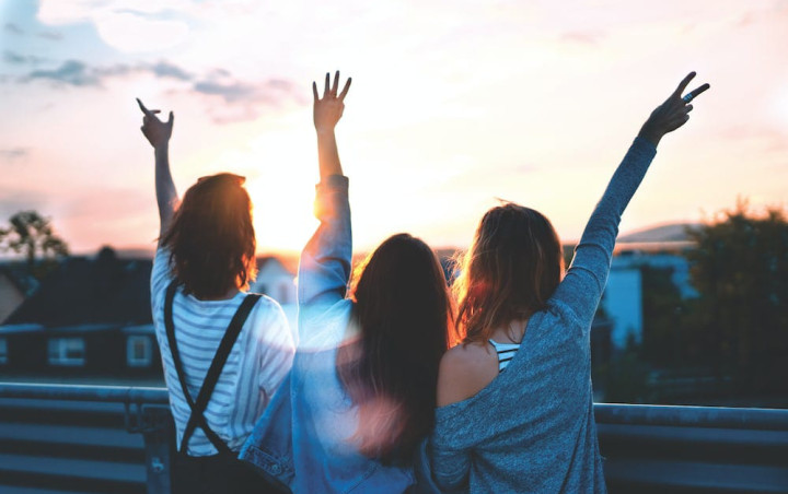 Tres personas jóvenes mirando el atardecer.
